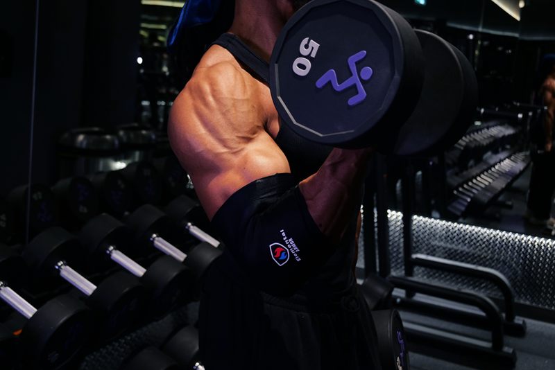 Athlete curling a dumbbell wearing the Elemental Armor Elbow Sleeve
