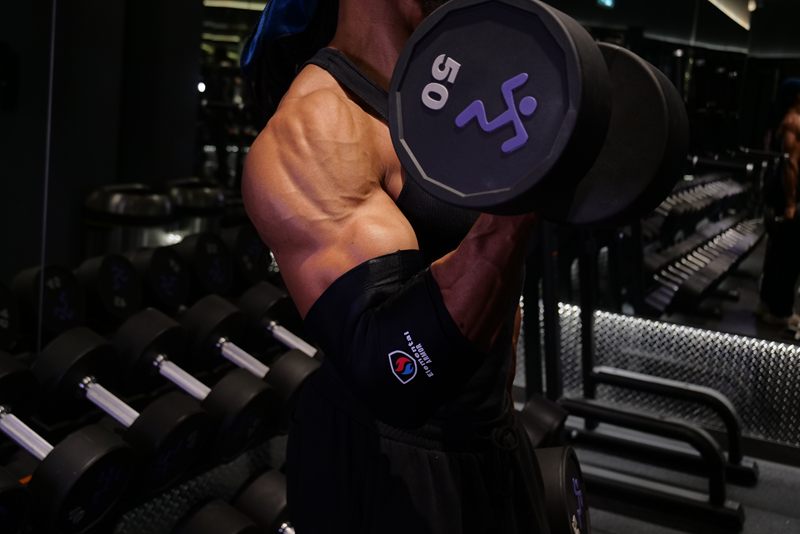 Athlete curling a dumbbell wearing the Elbow Sleeve