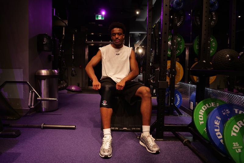 Athlete seated on a plyo box in the gym wearing the Knee Sleeve