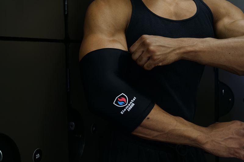 Athlete pulling the Elemental Armor Elbow Sleeve into place over the elbow
